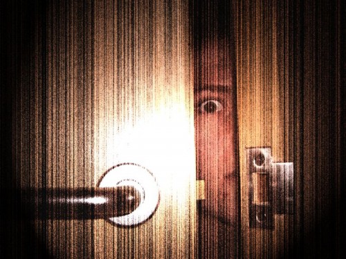 Scared, hiding behind the door