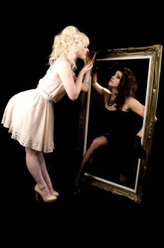 Two different types of women, looking at each other through a mirror