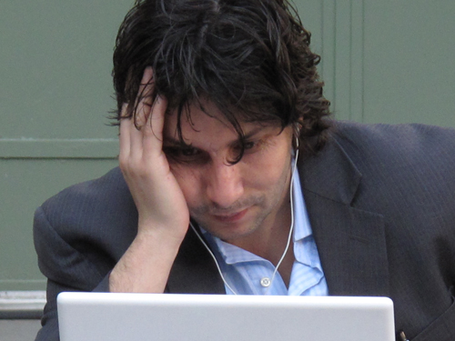 A man looking at his laptop screen dumbfounded